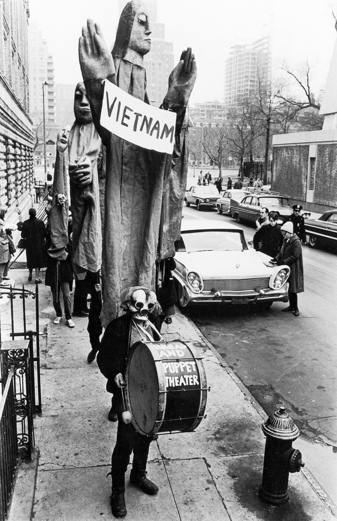In one of the first protests in New York City against the Vietnam War, masked members of the Bread and Puppet Theater, led by artist, writer, and director Peter Schumann, march down Thompson St. from Washington Square, March 15, 1965<br/>